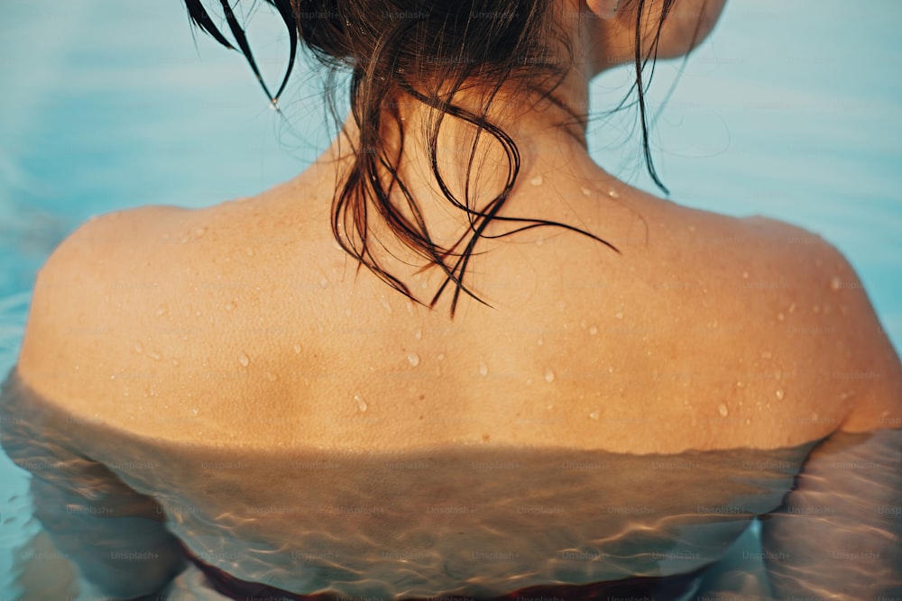 수영장에서 휴식을 취하는 아름다운 젊은 여성, 물방울이 있는 어깨가 닫힙니다. 거위 덩어리와 젖은 피부를 가진 갈색 머리 소녀의 뒷모습. 여름 방학. 여름 휴가 즐기기, 수영장에서 수영