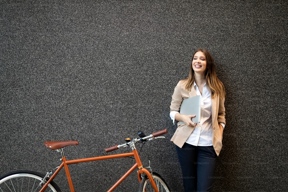 Young businesswoman standing in a city with bicycle and tablet