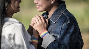 Cropped shot of young LGBT Lesbian holding her lover hand at the beautiful park with the blurred green grass as background. LGBT Happiness couple concept.