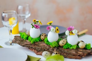 Close up of natural decoration for Easter table with eggs and flowers inside it on pine bark. Selective focus.