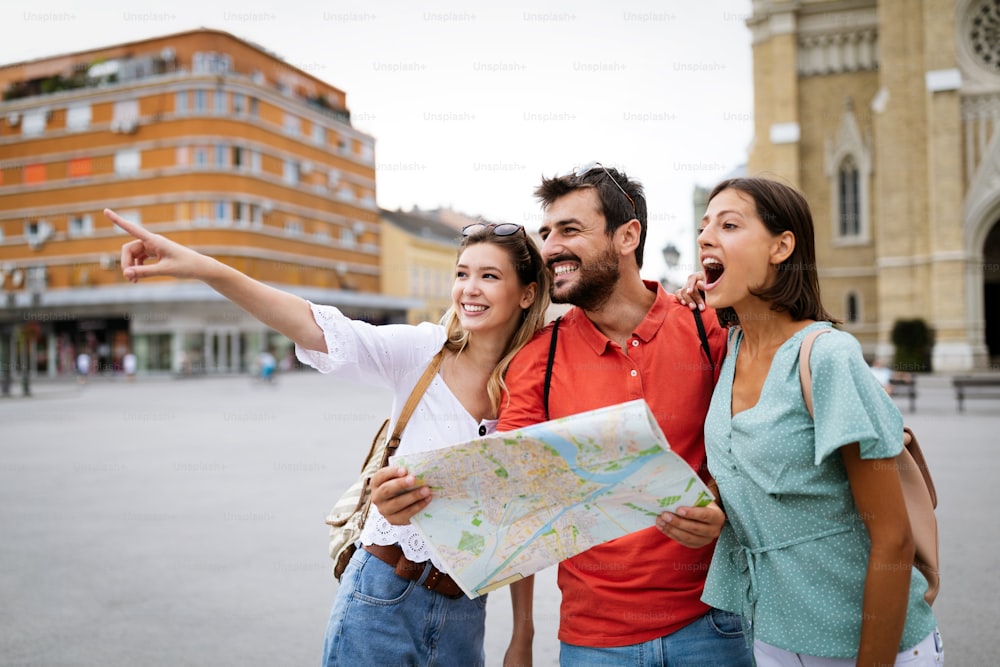 Feliz turistas viajantes amigos que visitam com o mapa na mão