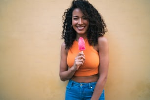 Porträt einer jungen Afroamerikanerin, die den Sommer genießt und ein Eis isst. Lifestyle-Konzept.