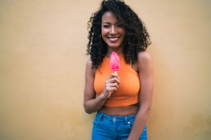 Portrait of young afro american woman enjoying summertime and eating an ice-cream. Lifestyle concept.