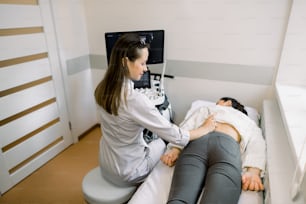 Gli ultrasuoni in fisioterapia. Terapeuta di una giovane donna che utilizza uno scanner a ultrasuoni sulla parte bassa della schiena della paziente femminile. Ecografia della schiena e dei reni.