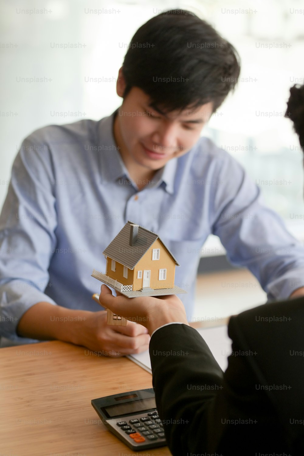 Close up view of Real estate agent holding house model while presenting to male customer to decision making sign contract agreement