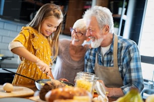 Meninas netos felizes tomando café da manhã com seus avós em casa