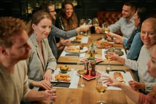 Gruppo di amici seduti in ristorante e cenatori.
