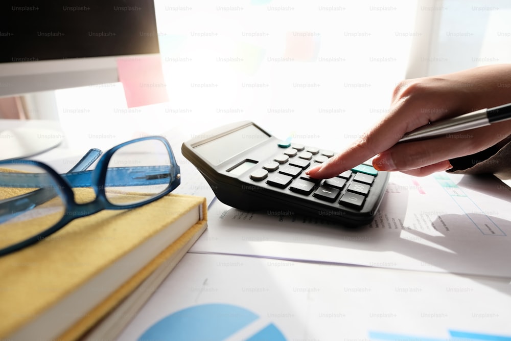 Primo piano Contabile utilizzando la calcolatrice per il calcolo delle spese finanziarie in ufficio a casa