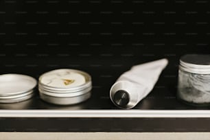 Déodorant en tube, dentifrice au charbon de bois en verre, shampoing solide en boîte en métal, après-shampoing dans une salle de bain moderne sur étagère noire. Concept zéro déchet. Sans plastique. Mode de vie durable