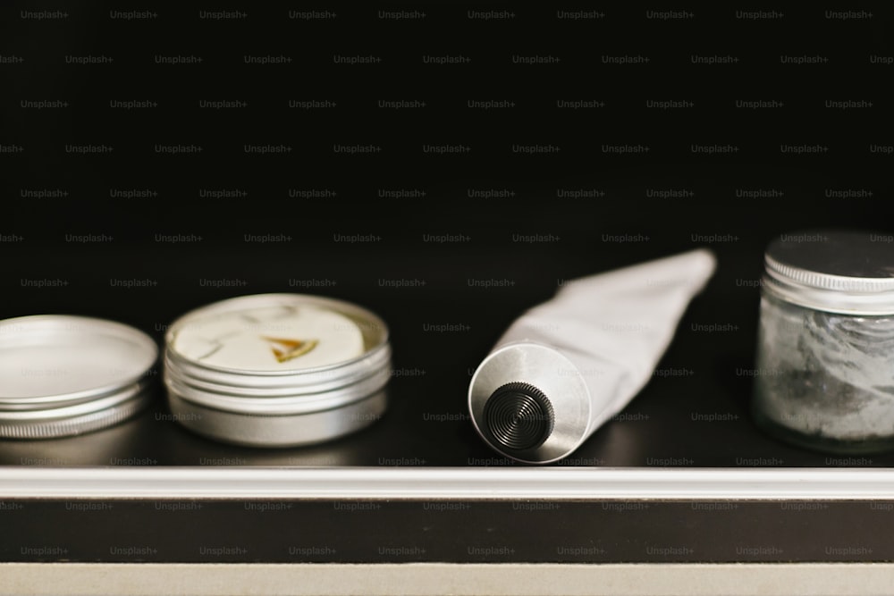 Deodorant in der Tube, Holzkohle-Zahnpasta in Glas, festes Shampoo in Metalldose, Conditioner im modernen Badezimmer auf schwarzem Regal. Zero-Waste-Konzept. Plastikfrei. Nachhaltiger Lebensstil