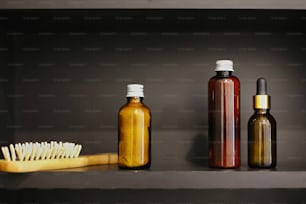Concepto de residuo cero. Esenciales naturales. Cepillo de pelo de madera sin plástico, ubtan para la piel en botella de vidrio, champú, acondicionador, tónico en vidrio en baño moderno en estante negro.