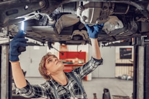 Girl checking the underbody of a light motor vehicle in a garage