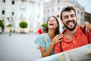 Summer holidays, dating and tourism concept. Smiling happy couple with map in the city