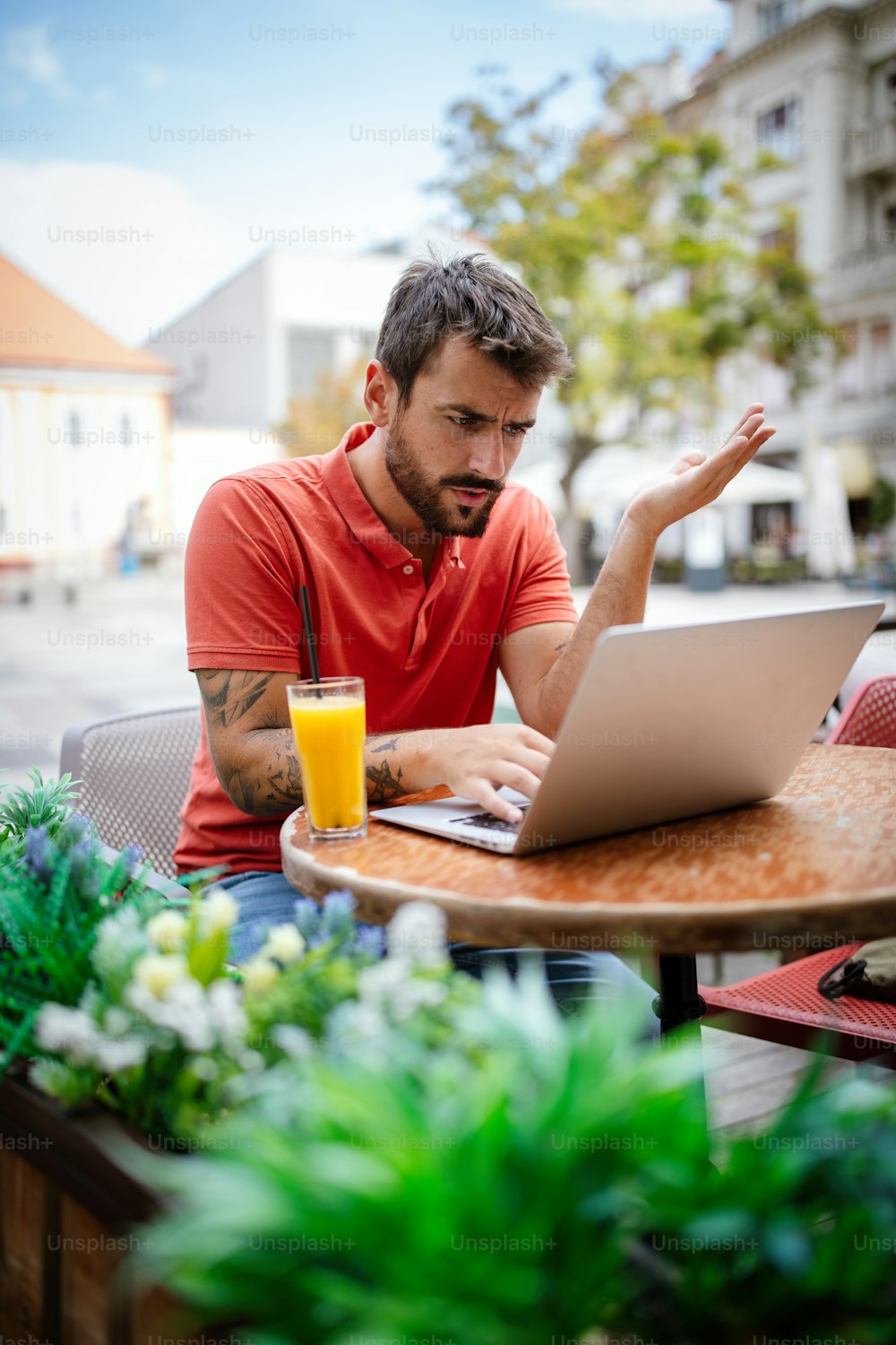 Joven estresado sentado frente a la computadora portátil en el café