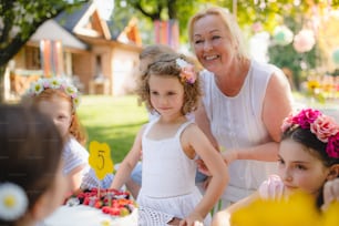 Group of small children sitting at the table outdoors on garden party.