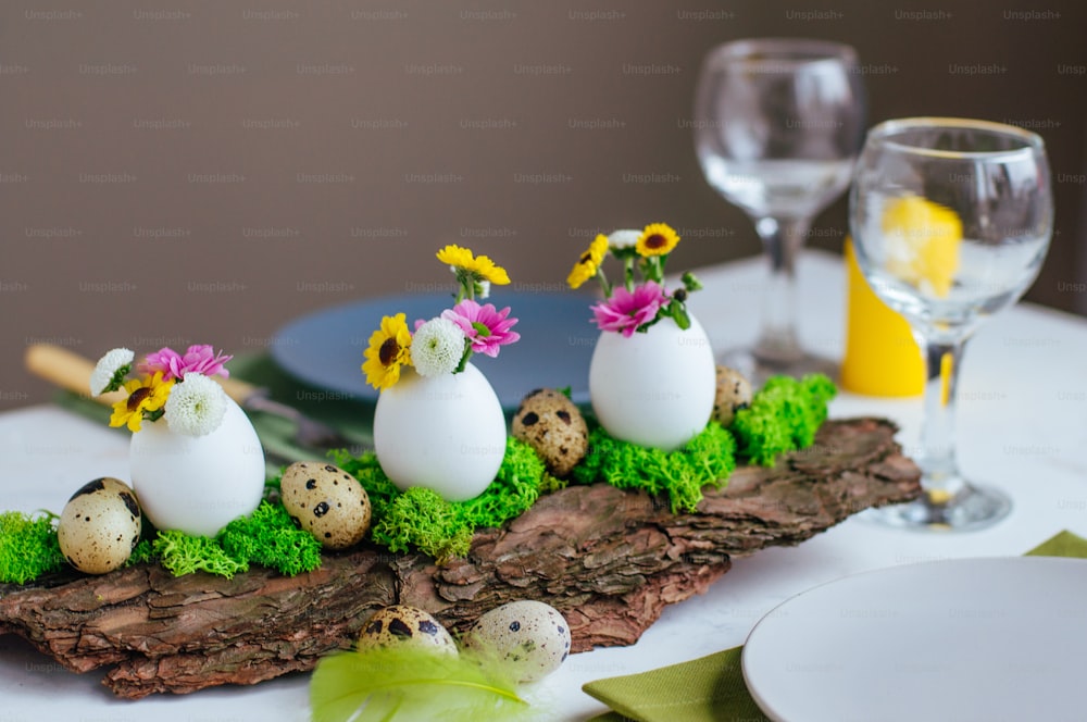 Close up of natural decoration for Easter table with eggs and flowers inside it on pine bark. Selective focus.