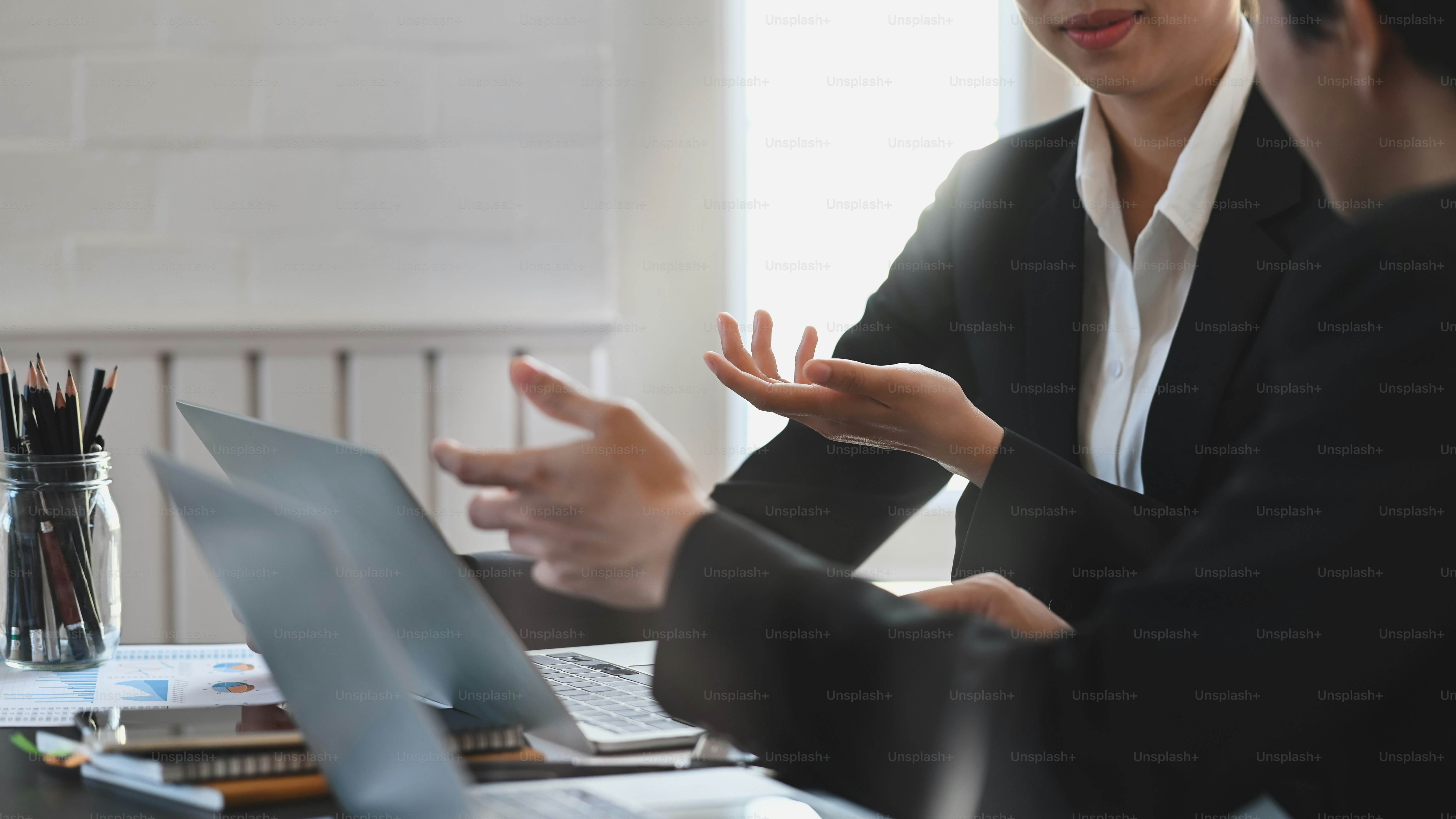 Business executive discussing/talking/meeting about their business plan while sitting at the modern meeting table with comfortable office as background.