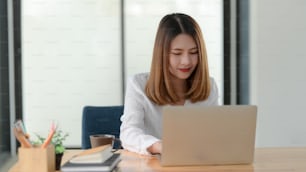 Close up view of female entrepreneur working while sitting at her working place in comfortable office room