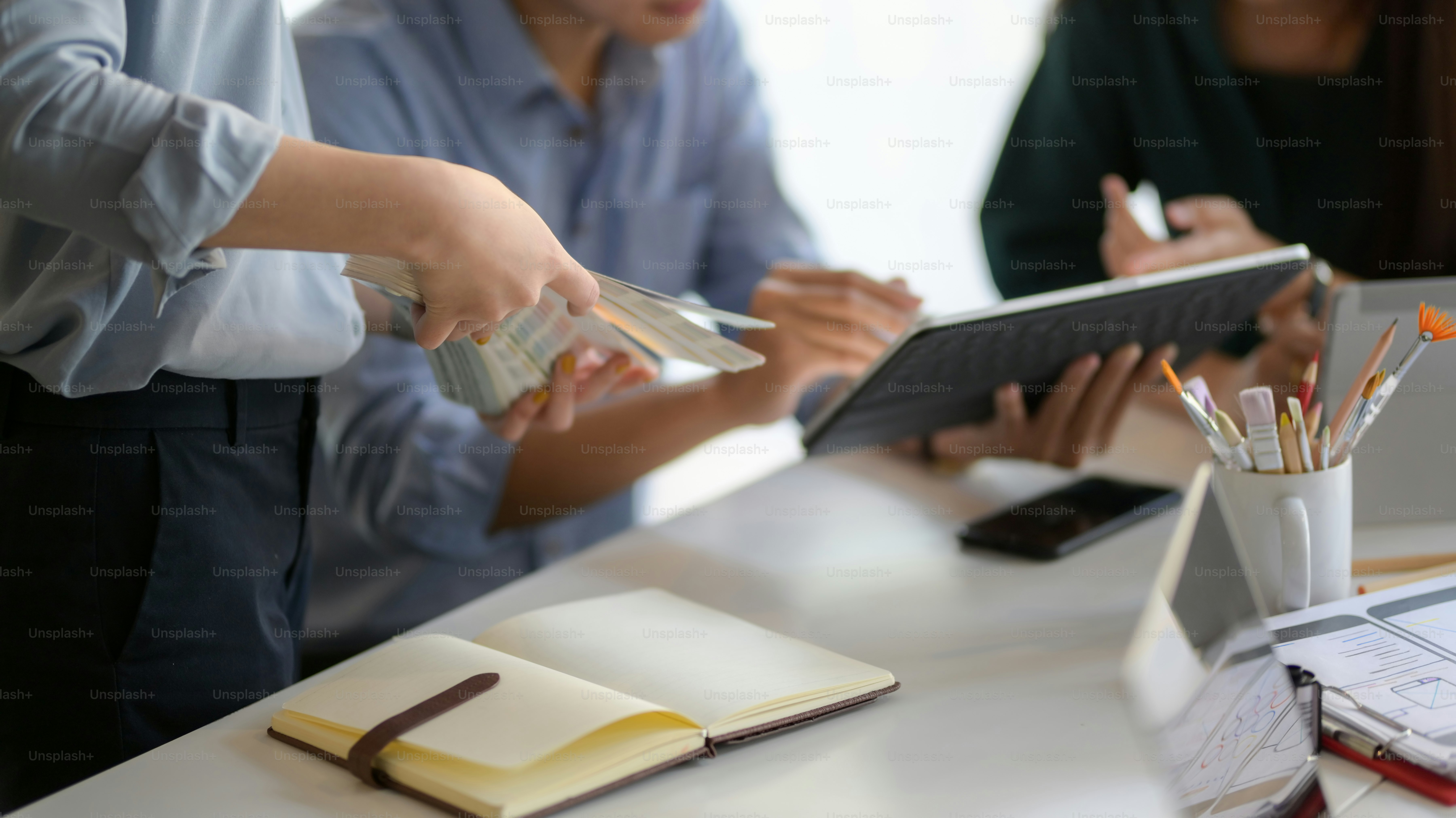 Close-up view of young UI graphic designer team planing their smartphone template together with laptop in office room