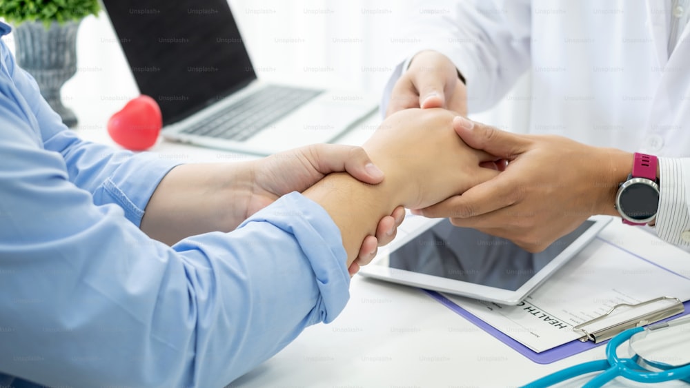 O médico do sexo masculino está examinando a dor no pulso do paciente.