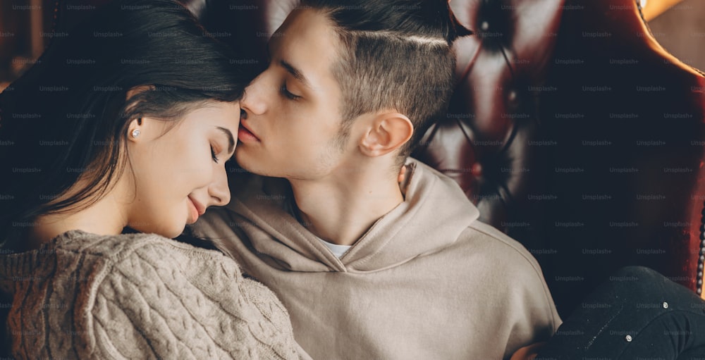 Beau couple caucasien aux cheveux noirs s’embrassant pendant le week-end tout en partageant leur chaleur et leur amour
