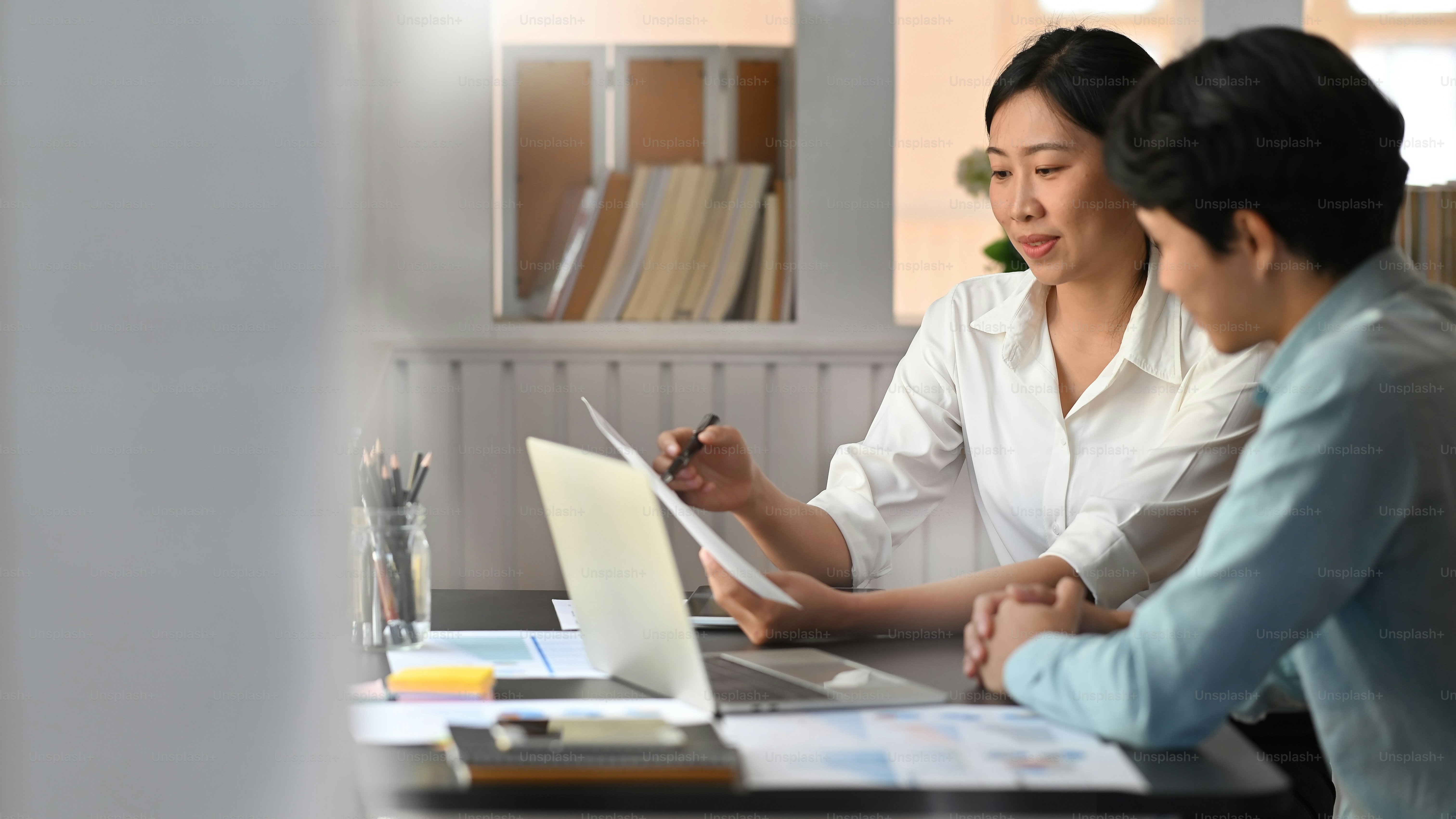 Business development team discussing/talking/meeting about their new project while sitting at the modern meeting table with comfortable office as background.