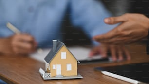 Cropped shot of Real estate agent offer house insurance or house ownership to smart man in blue shirt at the modern wooden table. Signing on agreement, Broker/Seller/Dealer concept.