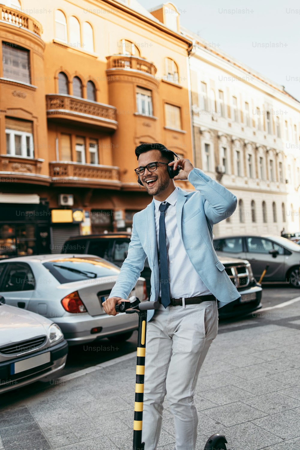 Young modern man using and driving electric scooter on city street and listens to music. Modern and ecological transportation concept.