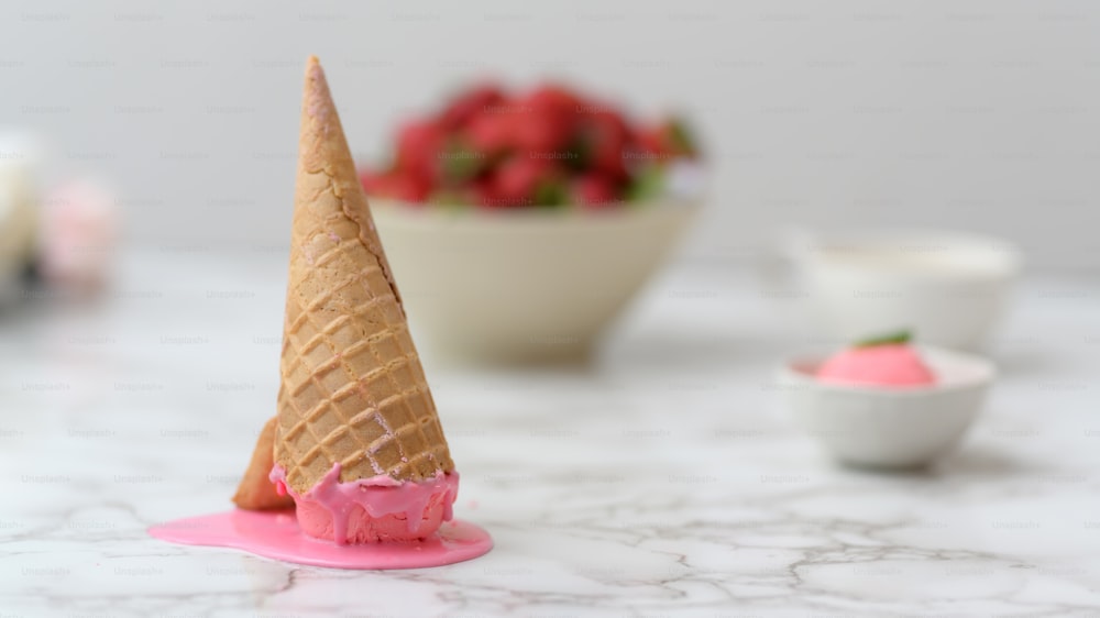 Close up view of strawberry ice-cream cone dropped and melting on marble desk