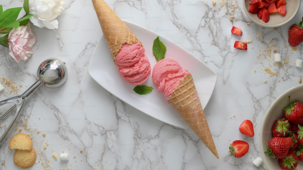 Vue de dessus d’un dessert d’été avec des cornets de crème glacée à saveur de fraise et une garniture sur fond de bureau en marbre