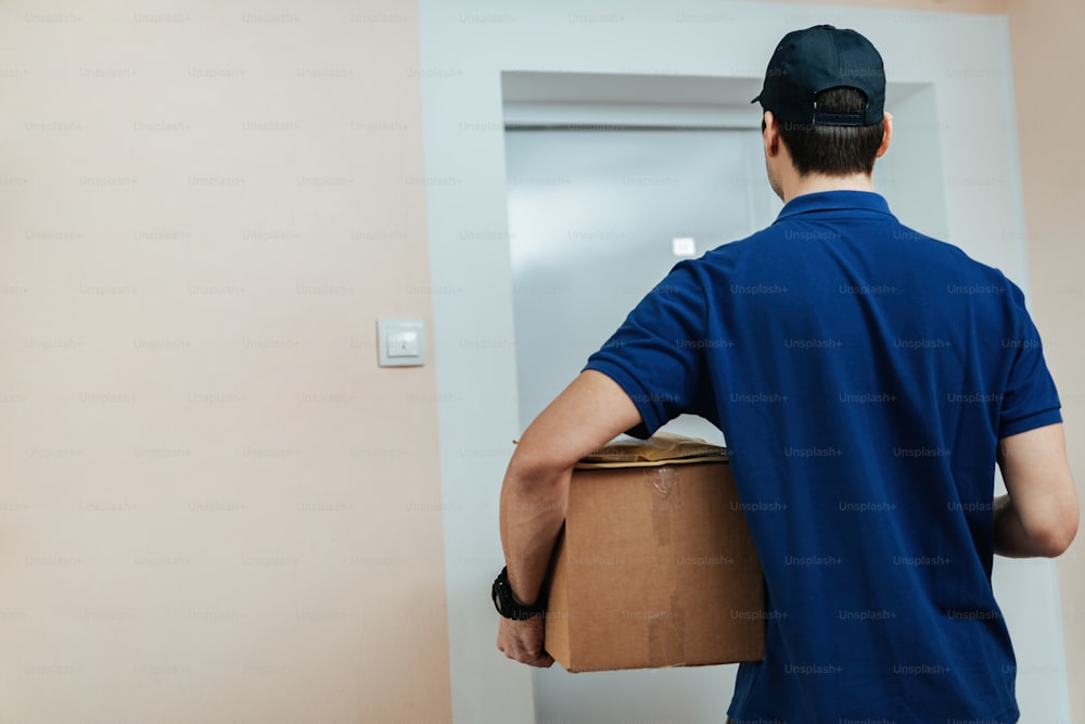 Rear view of delivery man holding packages while standing on a customer's doorway.