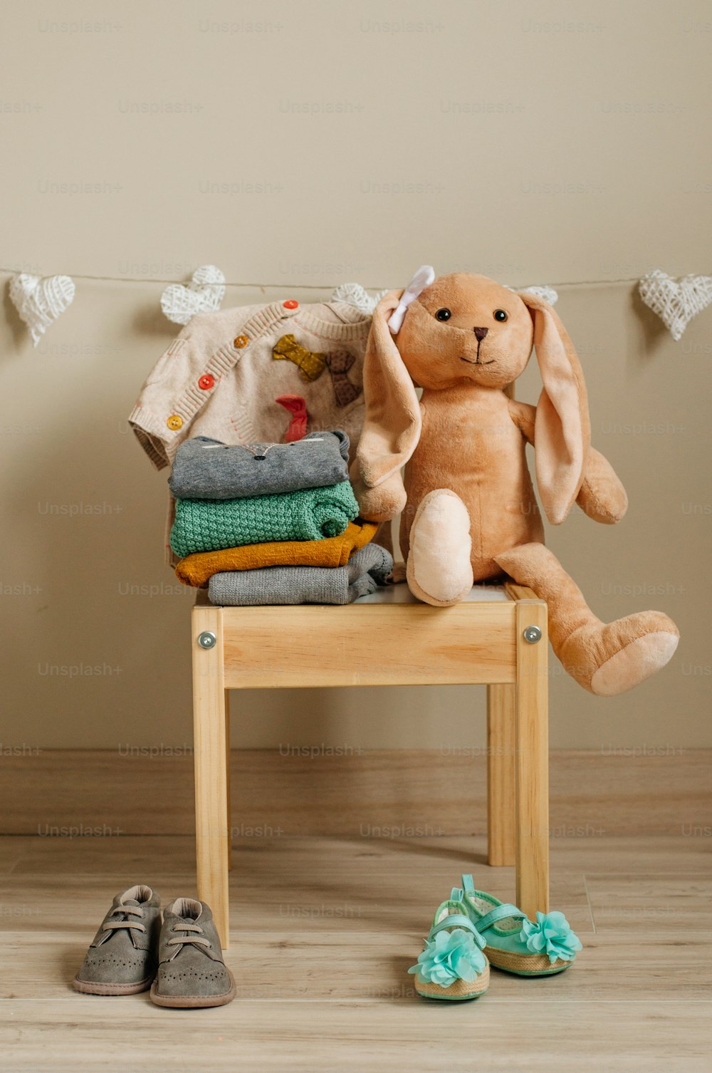 Organic cotton clothing and shoes, rabbit toy laying on the kids chair in children room. Selective focus.