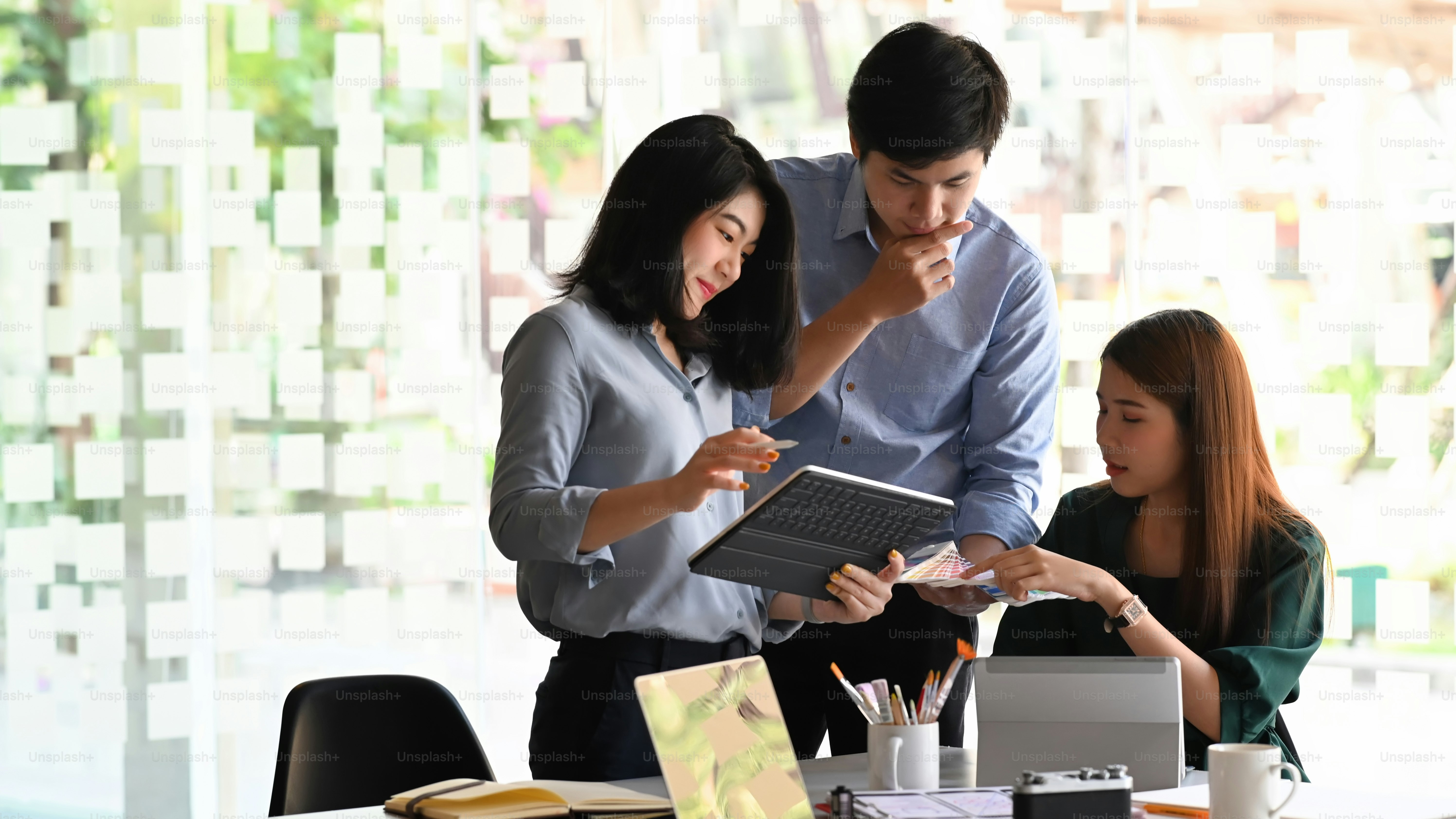 Photo of young business development team talking/discussing/brainstorming/meeting/planning about them new business project result at the meeting table with modern office/meeting room as background.