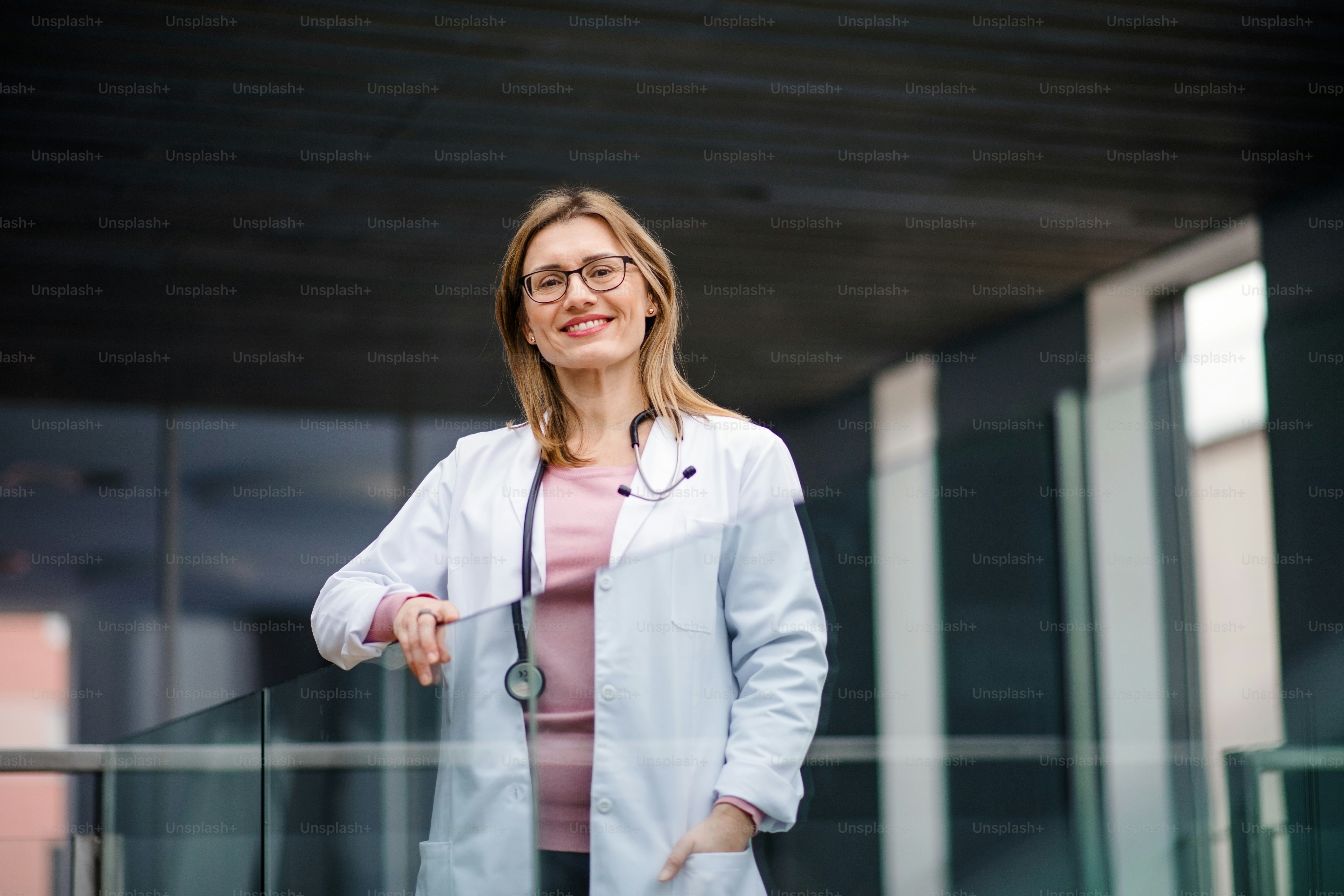 A portrait of female doctor standing on corridor, looking at camera.