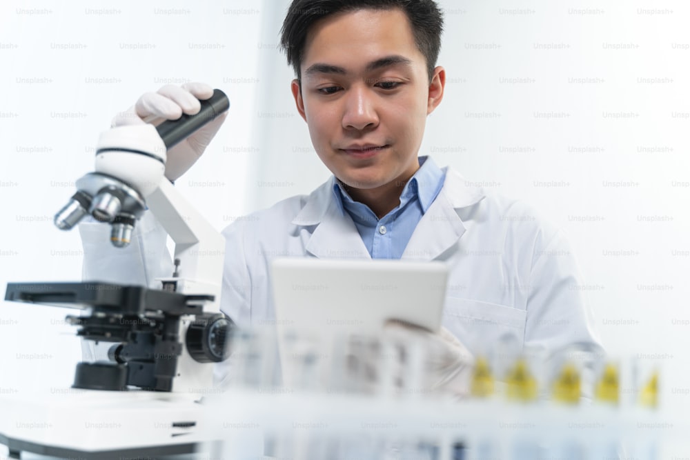 Kind Asian medical worker keeping smile on his face while inventing vaccine, science and research concept