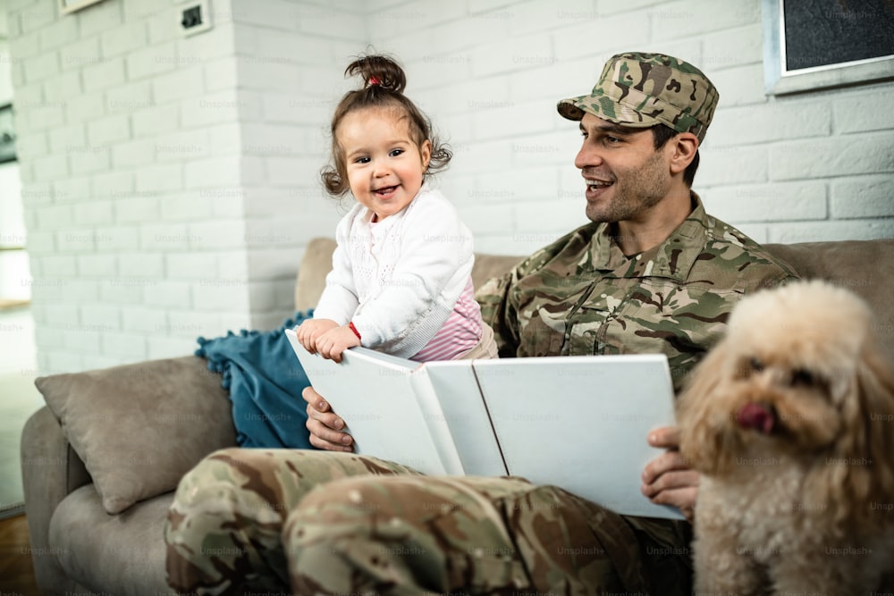 Happy military father and his daughter looking at photo album and having fun at home.