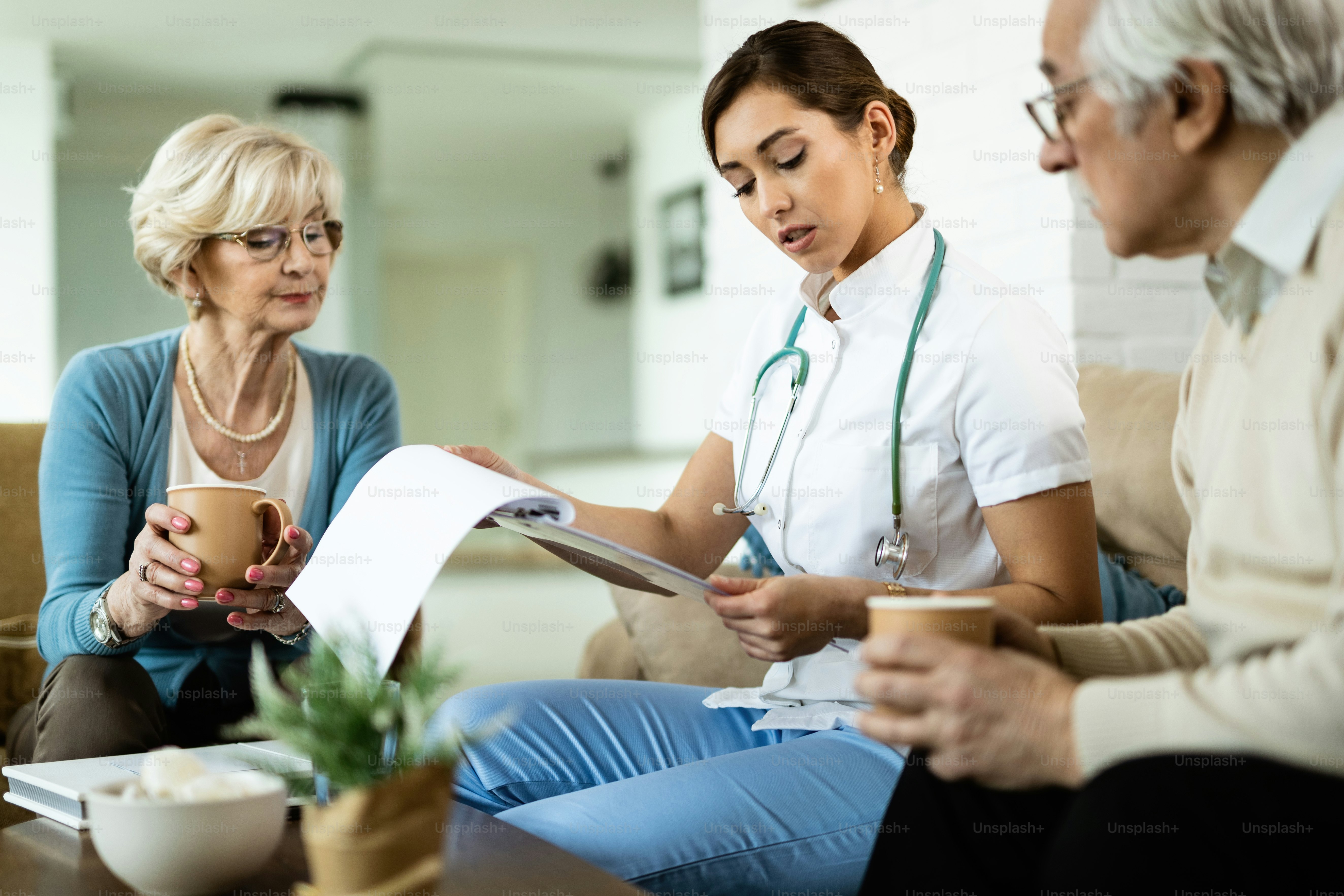 Young healthcare worker and senior couple analyzing medical test results during home visit.