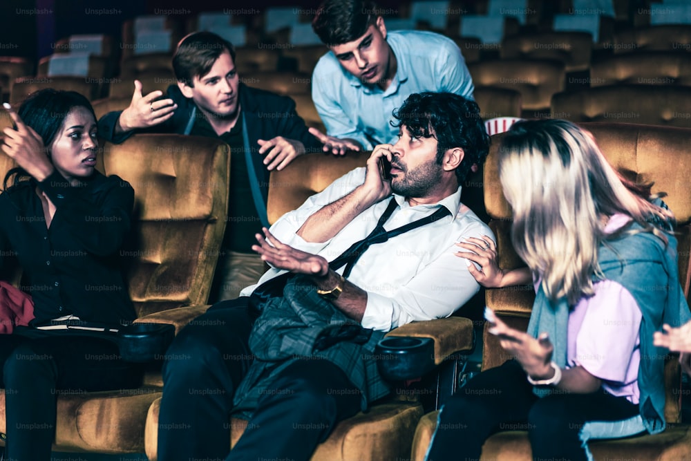 Annoying man talking on the mobile phone at the movie theater people in cinema is angry him