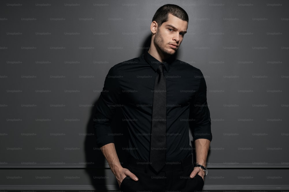 Young handsome businessman in black shirt. Confident young businessman posing on gray background