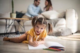 This is something new and fun for me. Family at home. Little girl writing on floor. Focus in on foreground.