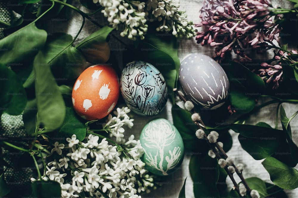 Huevos de Pascua con flores lilas sobre fondo rústico y sauce. concepto de tarjeta de felicitación. Vista superior. Huevo decorado colorido con adornos florales y de pollo. Vacaciones de primavera. Felices Pascuas