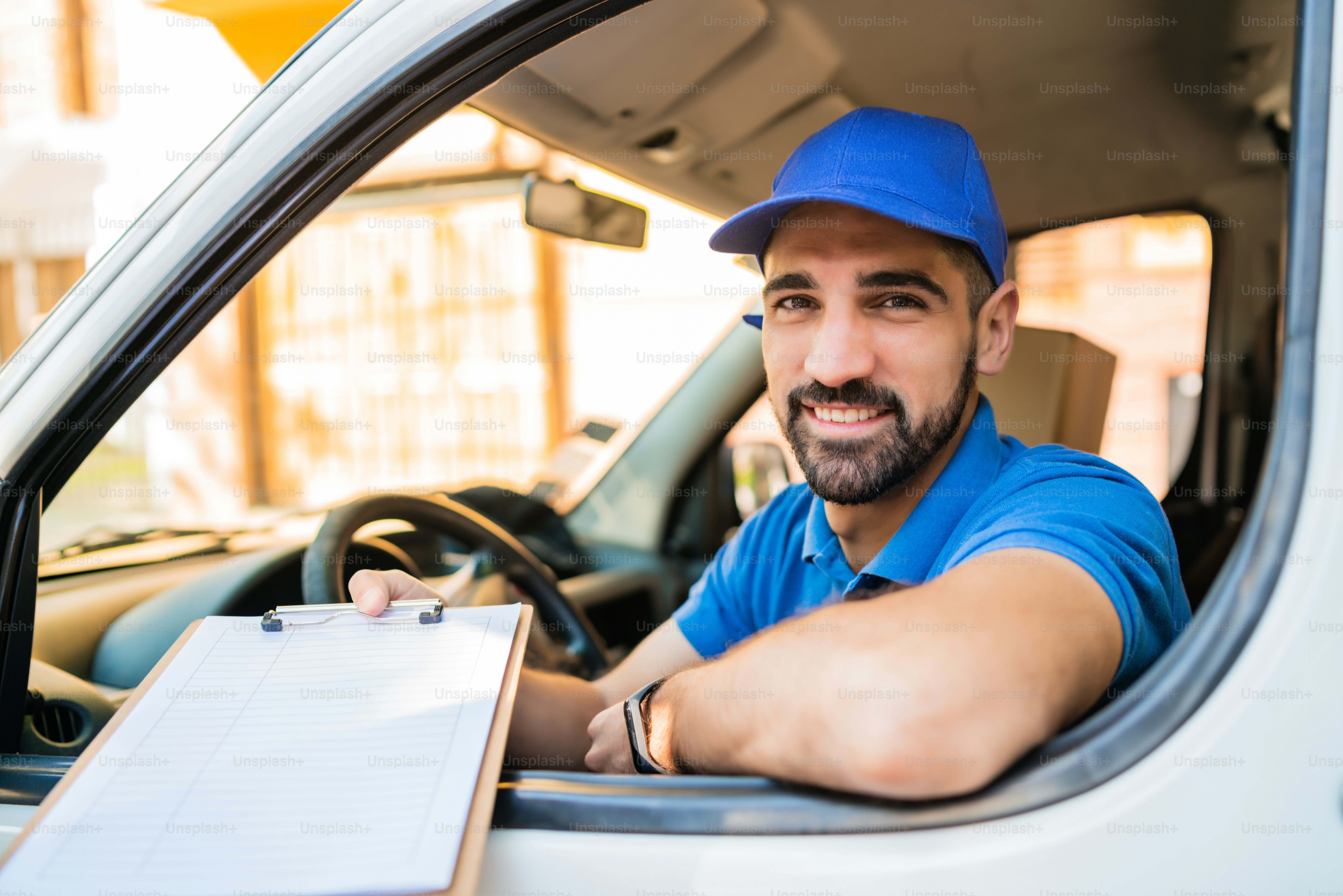 Portrait of a delivery man in van and giving clipboard to customer for ...