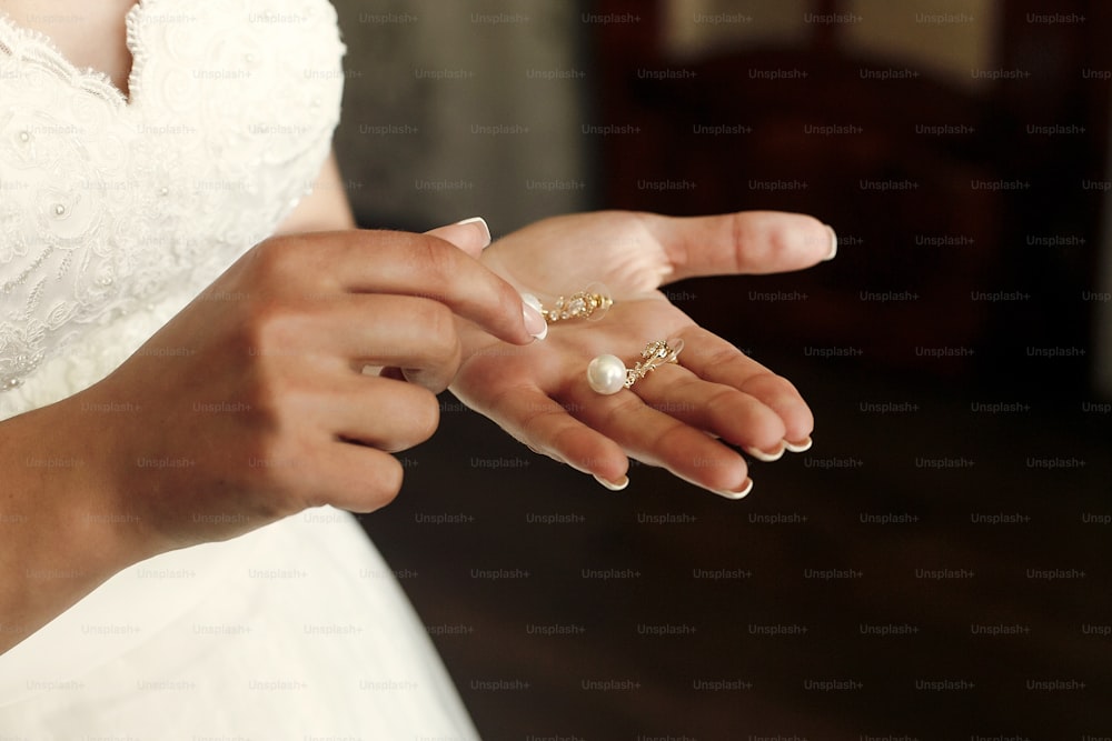 朝、花嫁の朝、結婚式の準備で高級真珠のイヤリングを手に持つ美しい花嫁