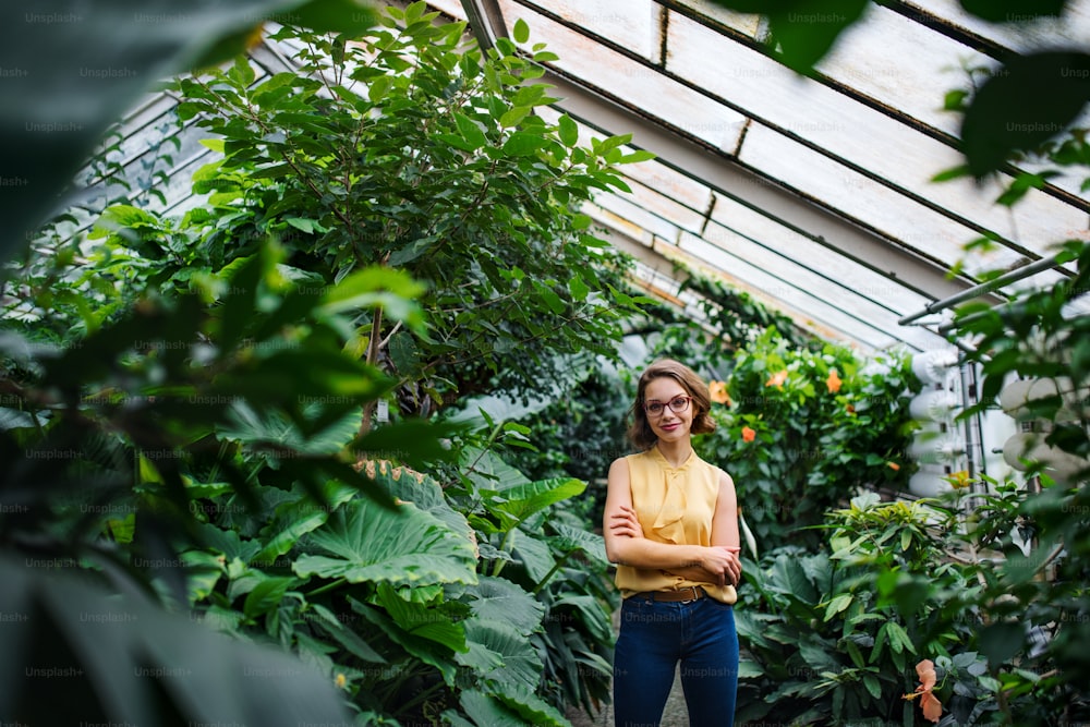 A young woman standing in greenhouse in botanical garden. Copy space.