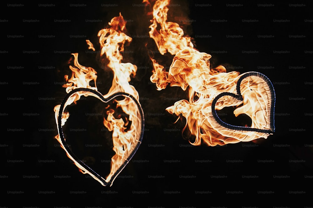 Dos fuegos artificiales en forma de corazones sobre fondo negro, espectáculo de fuego en la noche. Tarjeta de Feliz Día de San Valentín. Fuego de Bengala corazón ardiente. espacio para el texto. Concepto de boda o San Valentín