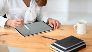 Cropped image of businesswoman holding and drawing on computer tablet in her hands at the modern office.
