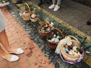 Comida tradicional ortodoxa de Pascua para la bendición. Cestas de Pascua con elegantes huevos pintados, pastel de Pascua, jamón, mantequilla, vela con ramas de boj para santificar en la iglesia