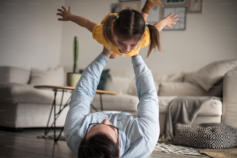 Fly my little bird. Father and daughter having fun at home.