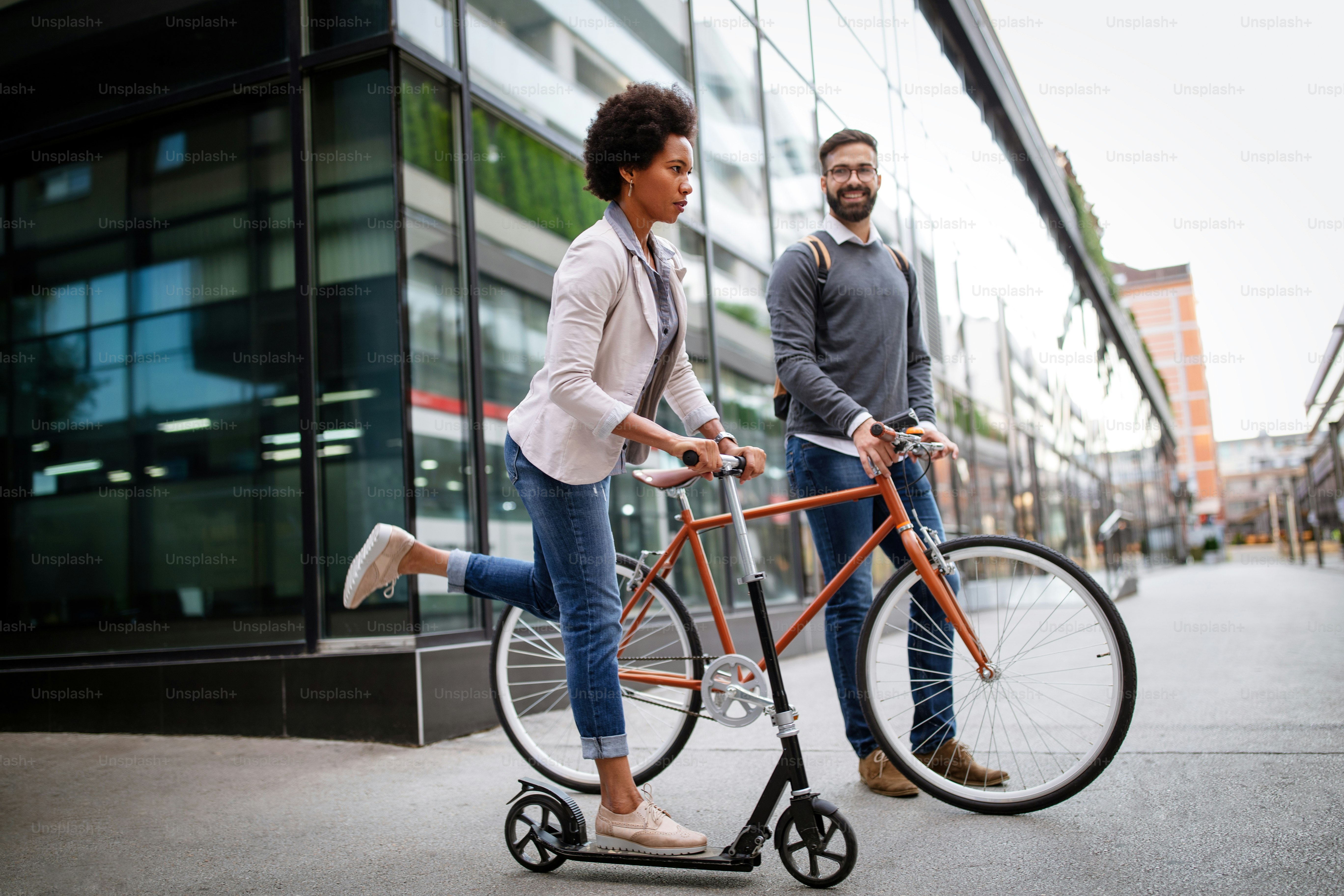 Gente de negocios ecológica feliz que va a trabajar con bicicleta, scooter eléctrico en la calle urbana