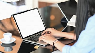 Foto einer jungen Frau, die auf dem Computer-Laptop tippt, während sie am modernen Schreibtisch sitzt.